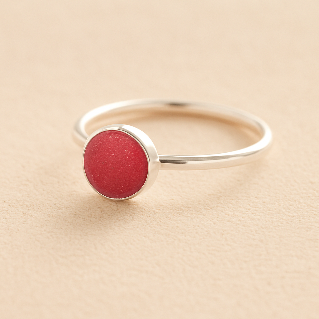 Sterling Silver ashes ring with a dark pink resin circle filled with ashes or fur on a beige background