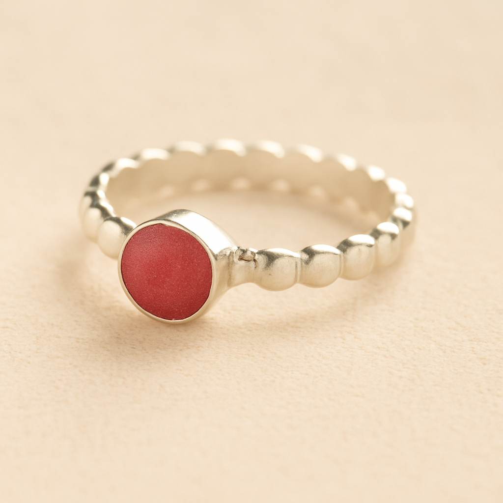 Silver bubble memorial ring with dark pink resin on a beige background.