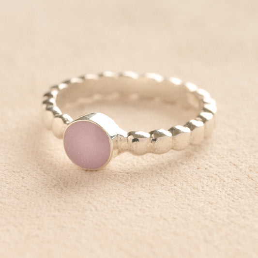 Silver bubble ashes ring with lavender resin on a beige background.