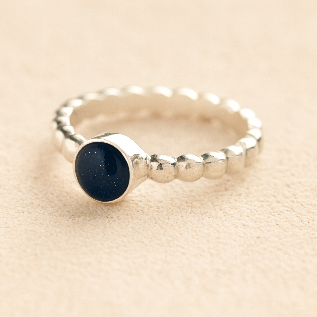 Silver bubble ashes ring with navy resin on a beige background.