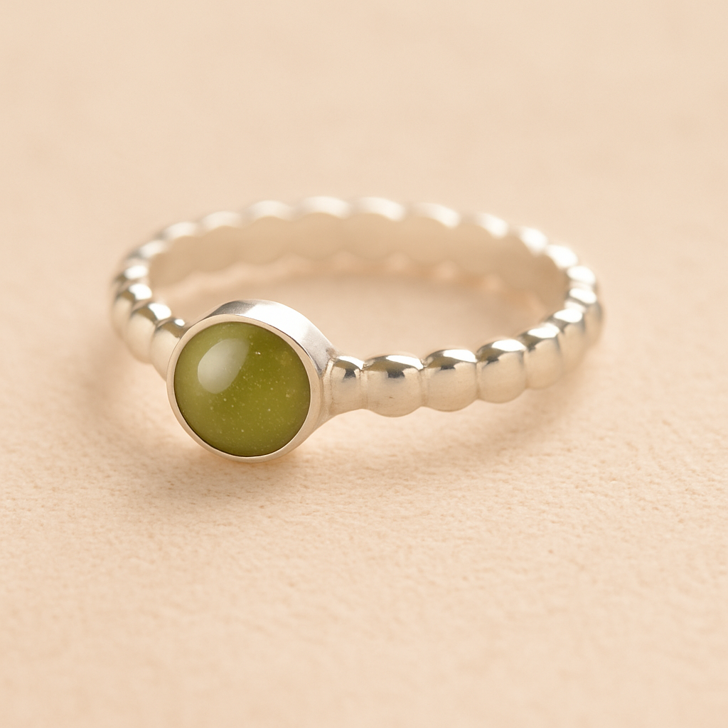 Silver bubble cremation ring with sage resin on a beige background.