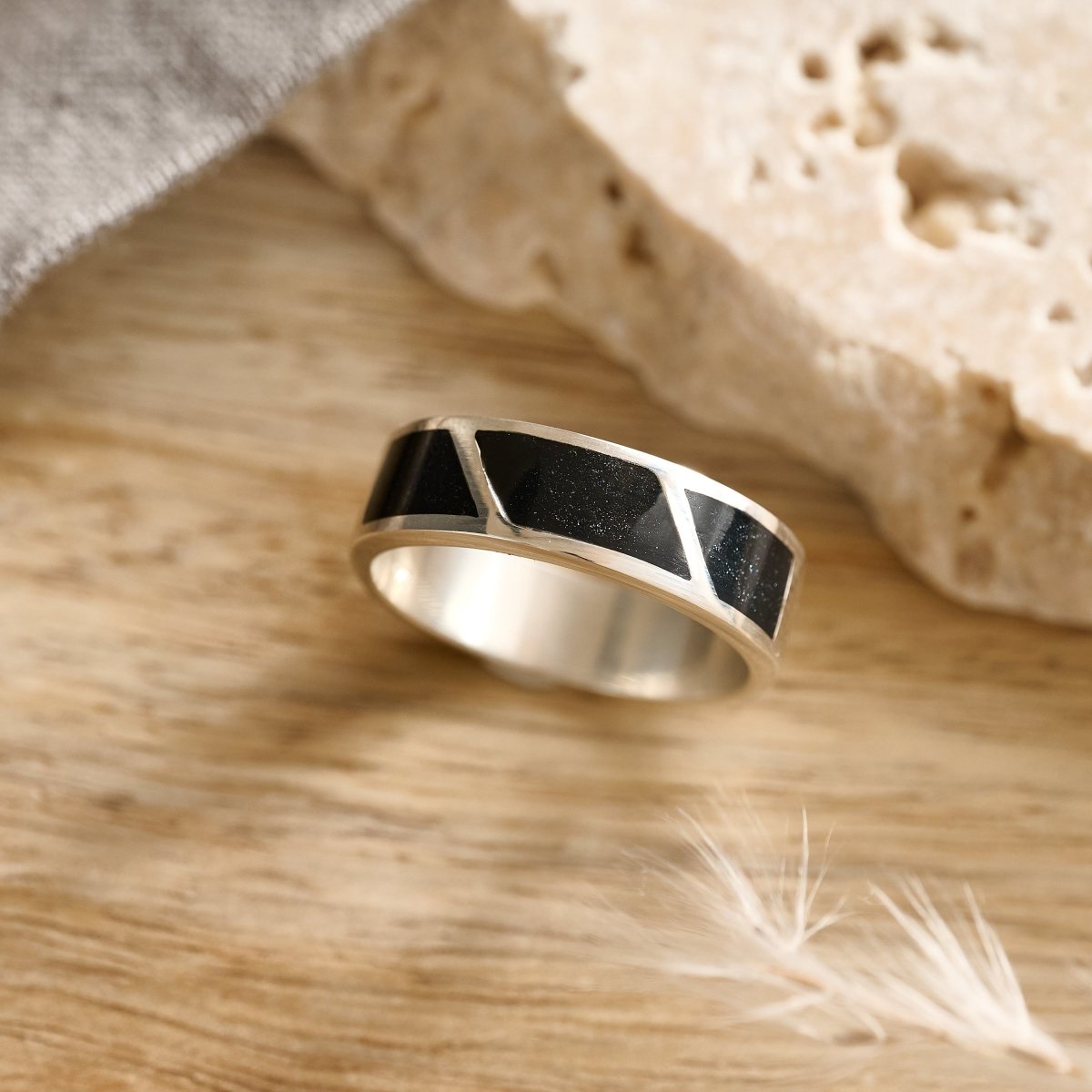Mens Silver ashes ring with black inlay on a wooden surface