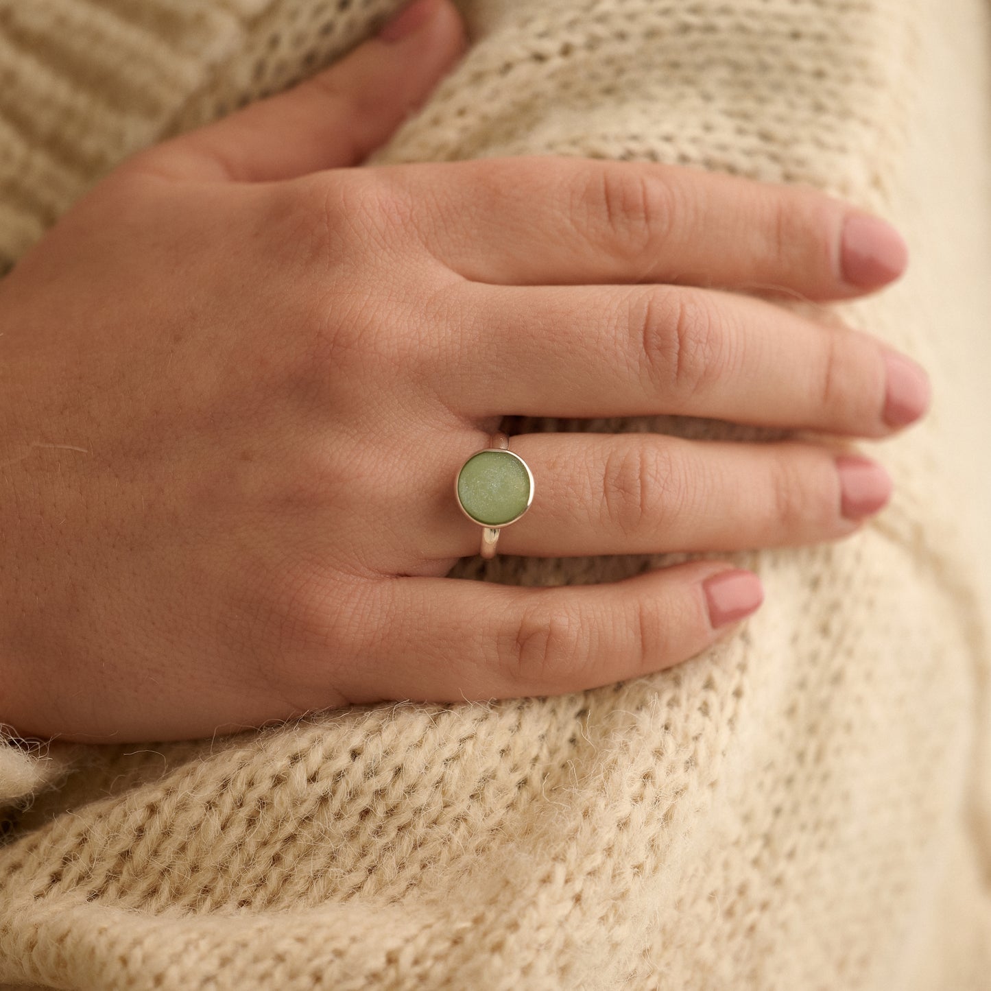 Sterling silver ashes ring with sage resin worn by woman holding her arm