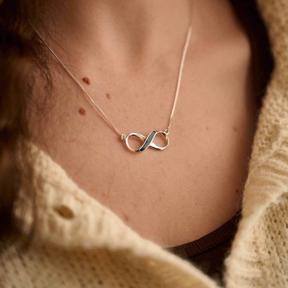 Infinity necklace with ashes in navy resin being worn by a female model