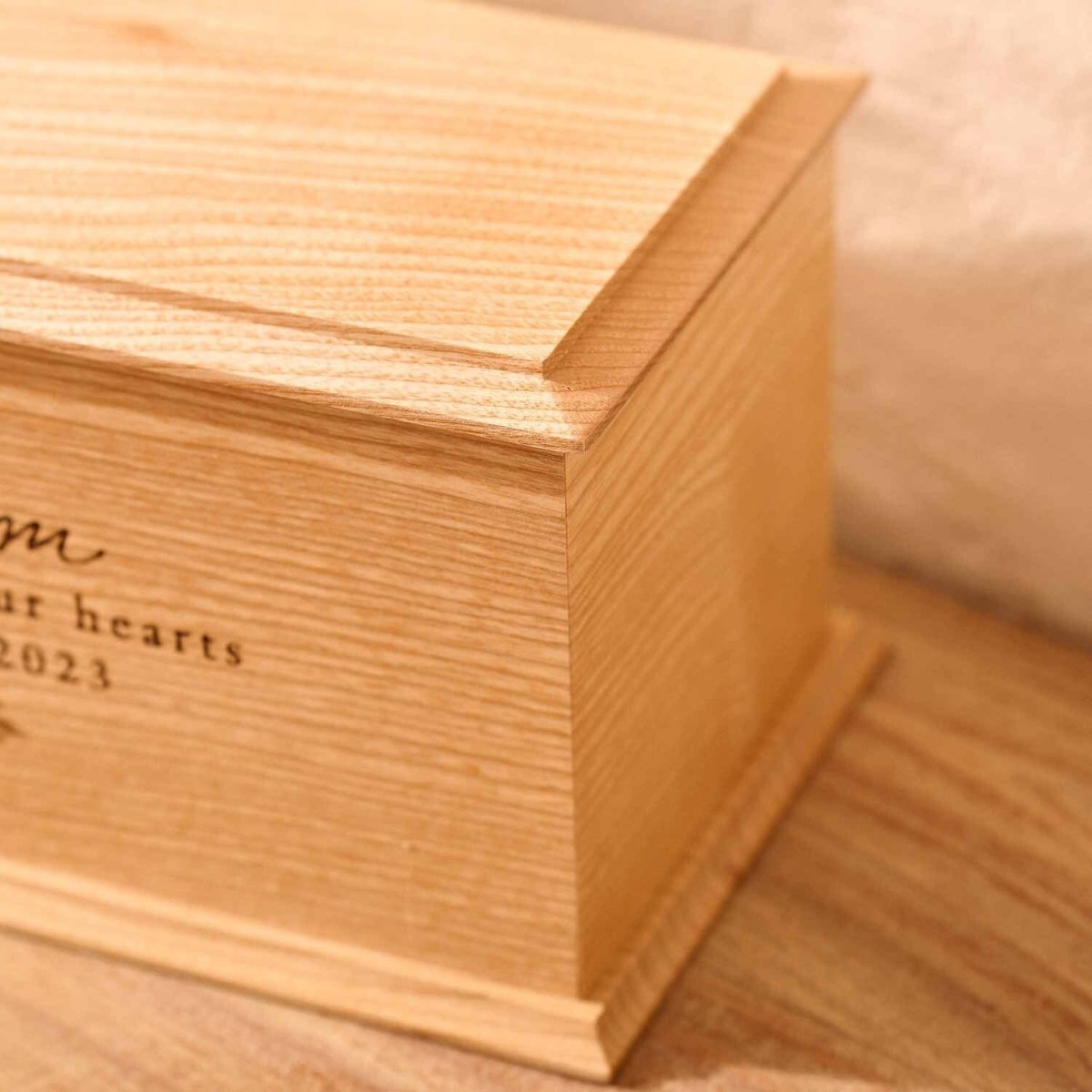 Close-up of engraved ash wood cremation urn with floral design for women – detailed view of custom memorial