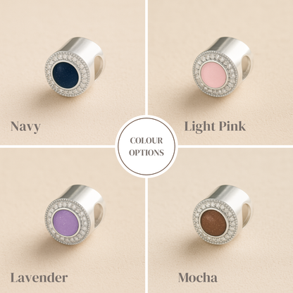 Four color options of a cremation bead with navy, light pink, lavender, and mocha centers on a beige background.