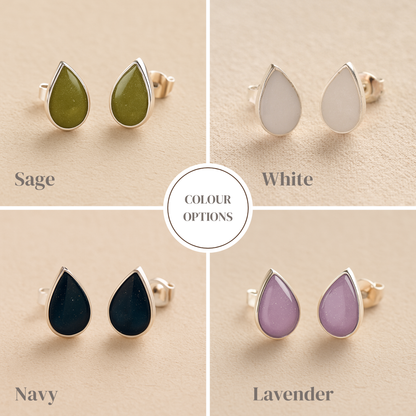 Teardrop-shaped Memorial earrings in sage, white, navy and lavender colors on a beige background.