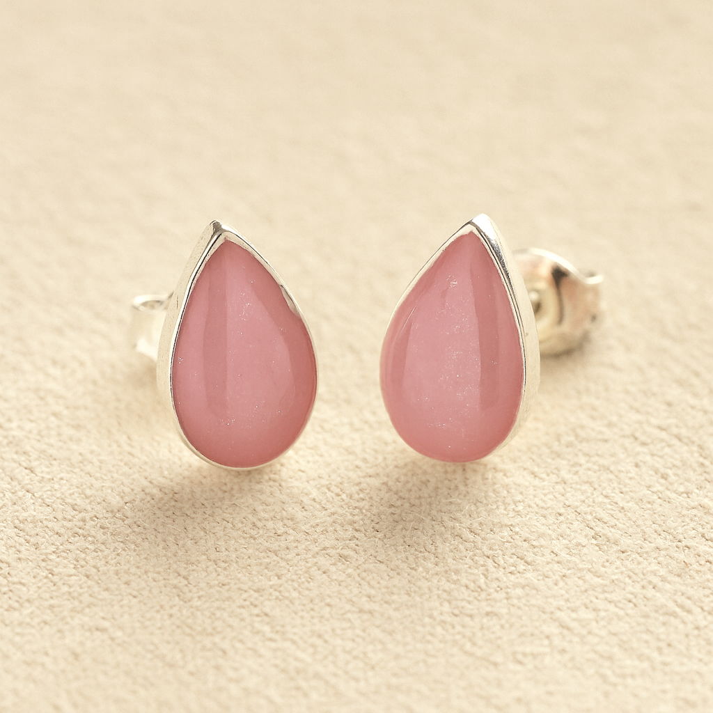 Silver Cremation Ashes Teardrop Earrings with light pink resin on a beige background