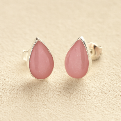 Silver Cremation Ashes Teardrop Earrings with light pink resin on a beige background