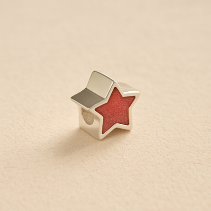 Silver star-shaped Memorial Charm Bead with dark pink resin on a beige background