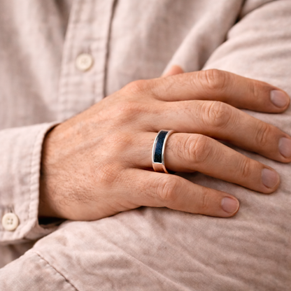 A man wearing an ashes ring with navy resin infill for ashes, hair or fur
