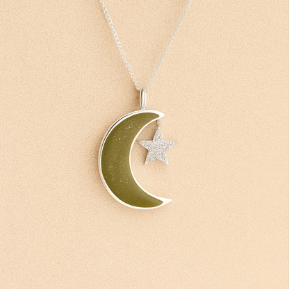 Moon and Star Memorial Necklace with sage resin filled with ashes or fur on a beige textured background