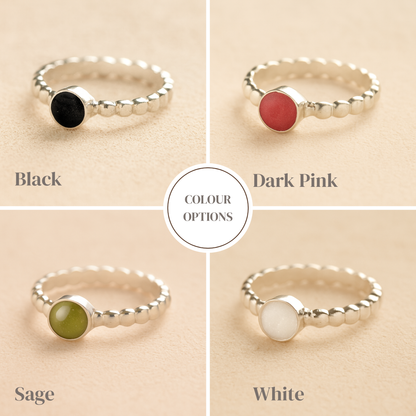 Four silver memorial rings with colored resin on a beige background, labeled 'Black', 'Dark Pink', 'Sage', and 'White'.