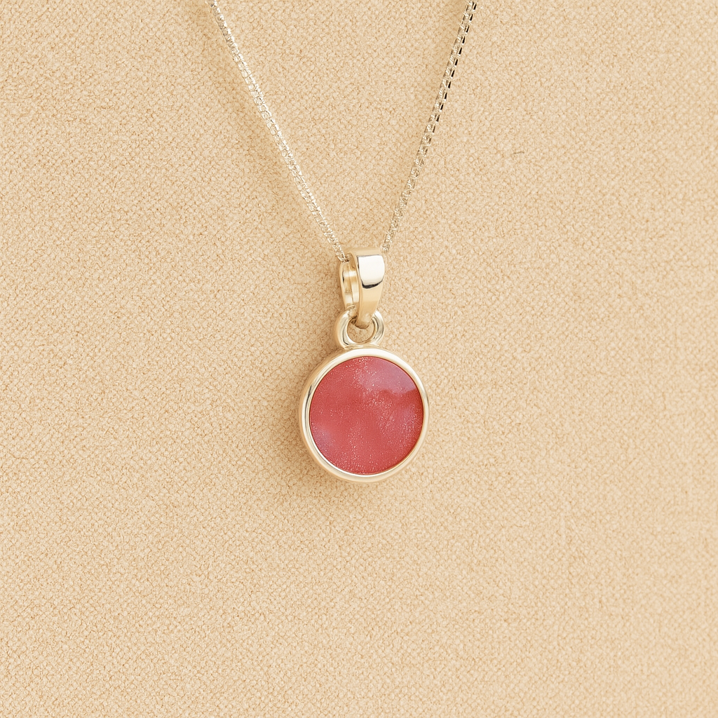 Silver Cremation ashes necklace with a round pendant and dark pink resin filled with ashes or fur, displayed on a soft beige background – suitable for pet or human memorials.