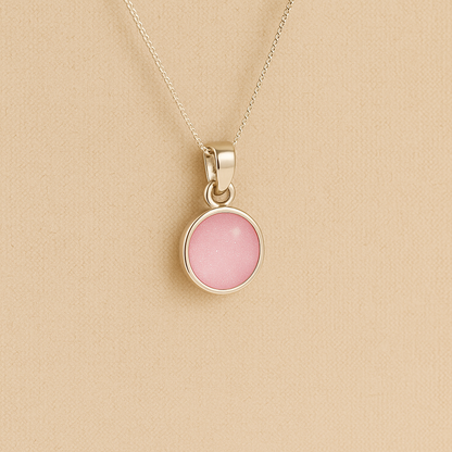 A round Silver Cremation ashes necklace light pink resin filled with ashes or fur, displayed on a soft beige background – suitable for pet or human memorials.
