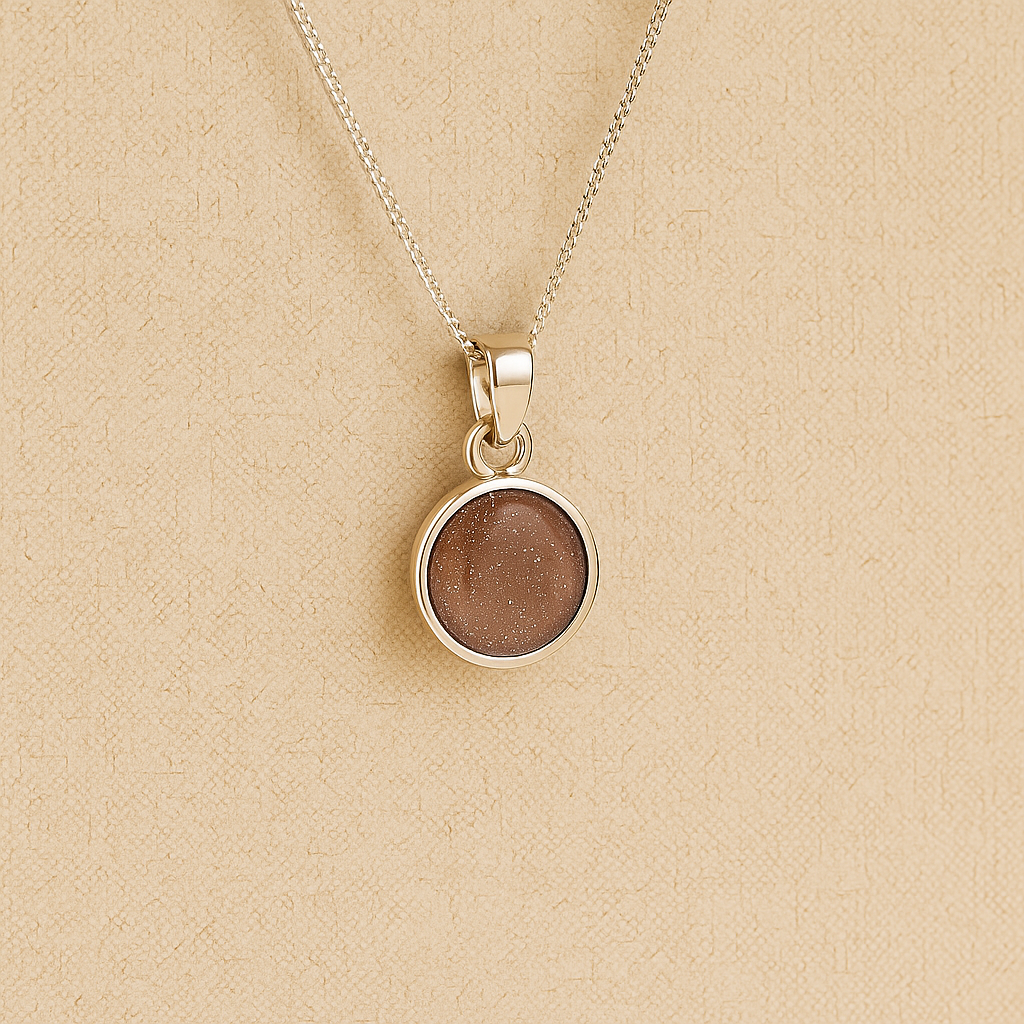 A round Silver Cremation ashes necklace mocha resin filled with ashes or fur, displayed on a soft beige background – suitable for pet or human memorials.