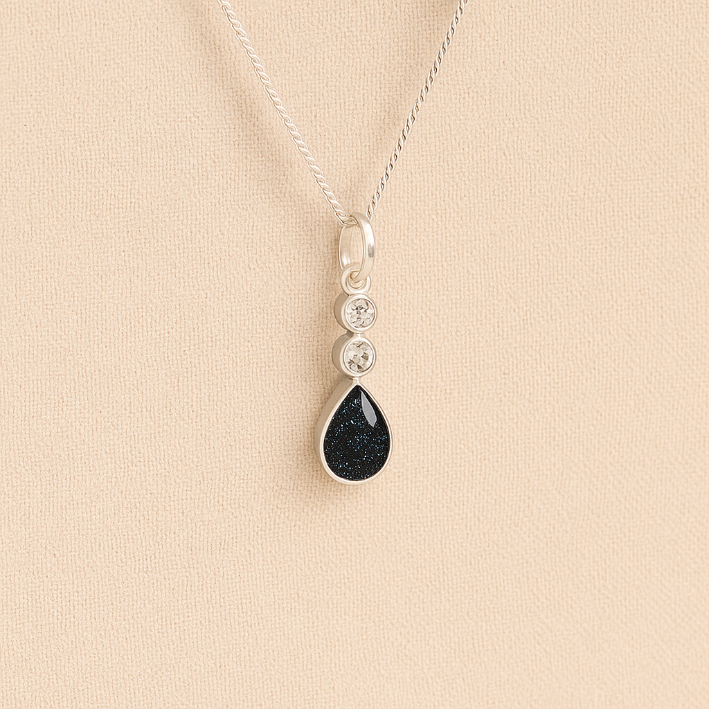 Silver Cremation ashes necklace with a teardrop pendant and black resin filled with ashes or fur, displayed on a soft beige background – suitable for pet or human memorials.