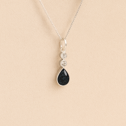 Silver Cremation ashes necklace with a teardrop pendant and black resin filled with ashes or fur, displayed on a soft beige background – suitable for pet or human memorials.