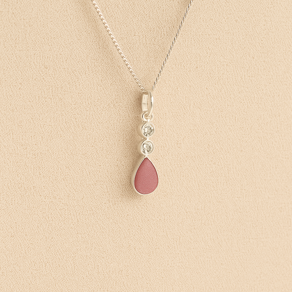 Silver Cremation ashes necklace with a teardrop pendant and dark pink resin filled with ashes or fur, displayed on a soft beige background – suitable for pet or human memorials.