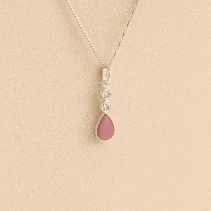 Silver Cremation ashes necklace with a teardrop pendant and dark pink resin filled with ashes or fur, displayed on a soft beige background – suitable for pet or human memorials.