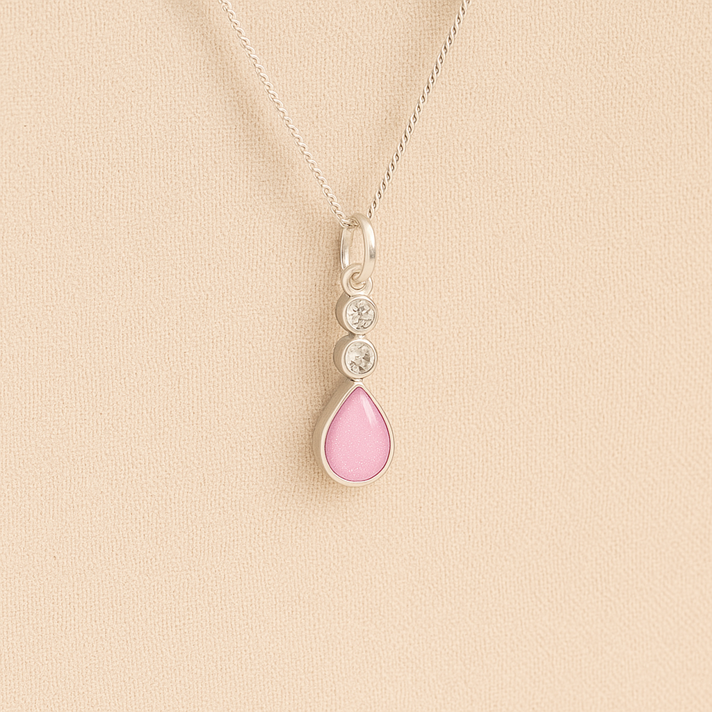 Silver Cremation ashes necklace with a teardrop pendant and light pink resin filled with ashes or fur, displayed on a soft beige background – suitable for pet or human memorials.
