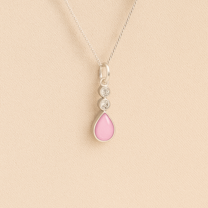 Silver Cremation ashes necklace with a teardrop pendant and light pink resin filled with ashes or fur, displayed on a soft beige background – suitable for pet or human memorials.
