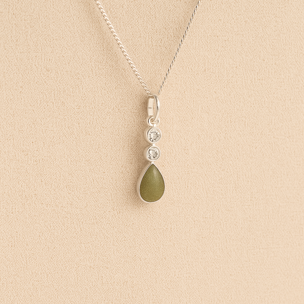 Silver Cremation ashes necklace with a teardrop pendant and sage resin filled with ashes or fur, displayed on a soft beige background – suitable for pet or human memorials.