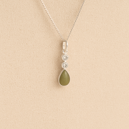 Silver Cremation ashes necklace with a teardrop pendant and sage resin filled with ashes or fur, displayed on a soft beige background – suitable for pet or human memorials.