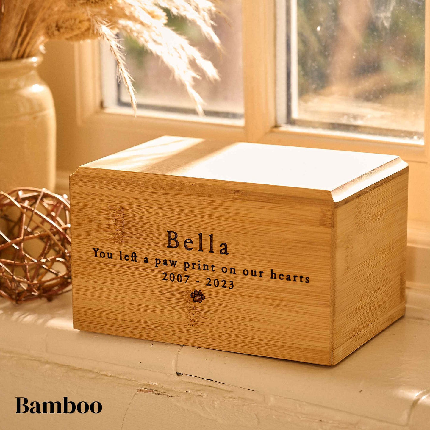 Bamboo wood dog or cat cremation urn with custom engraving. It is a cremation urn for pets with a pawprint engraved on it.