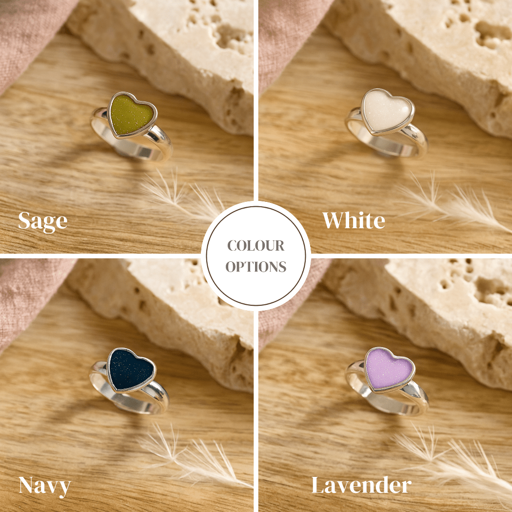 Heart-shaped cremated ashes ring with color options on a wooden surface