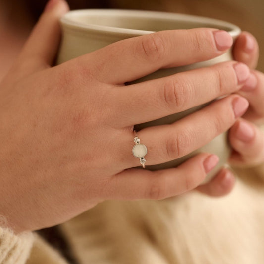 Woman wearing white cremation ashes ring with crystals while enjoying a tea in a reflective moment