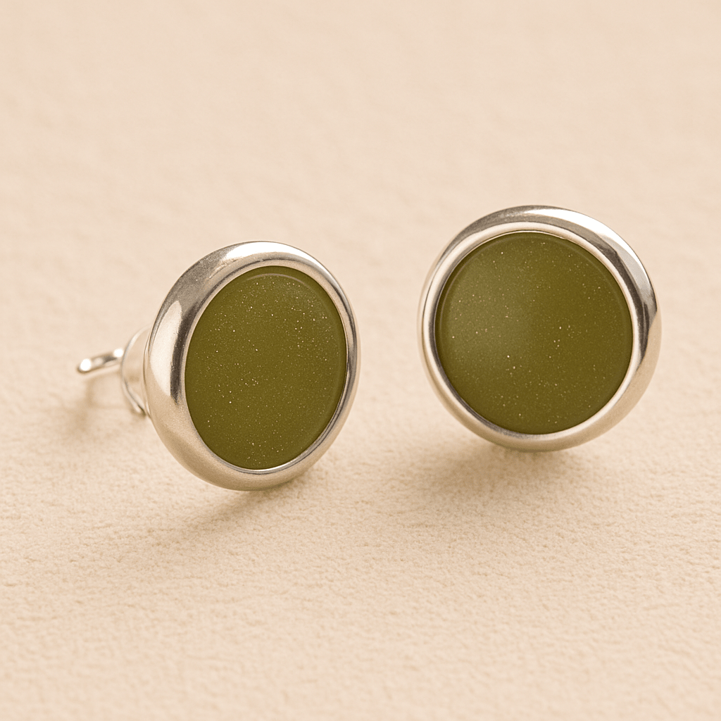 A pair silver round ashes earrings with sage resin in made from ashes, fur or hair set on a beige background