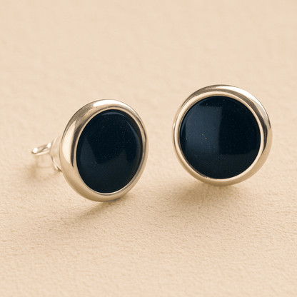 A pair silver round memorial earrings with navy resin in made from ashes, fur or hair set on a beige background