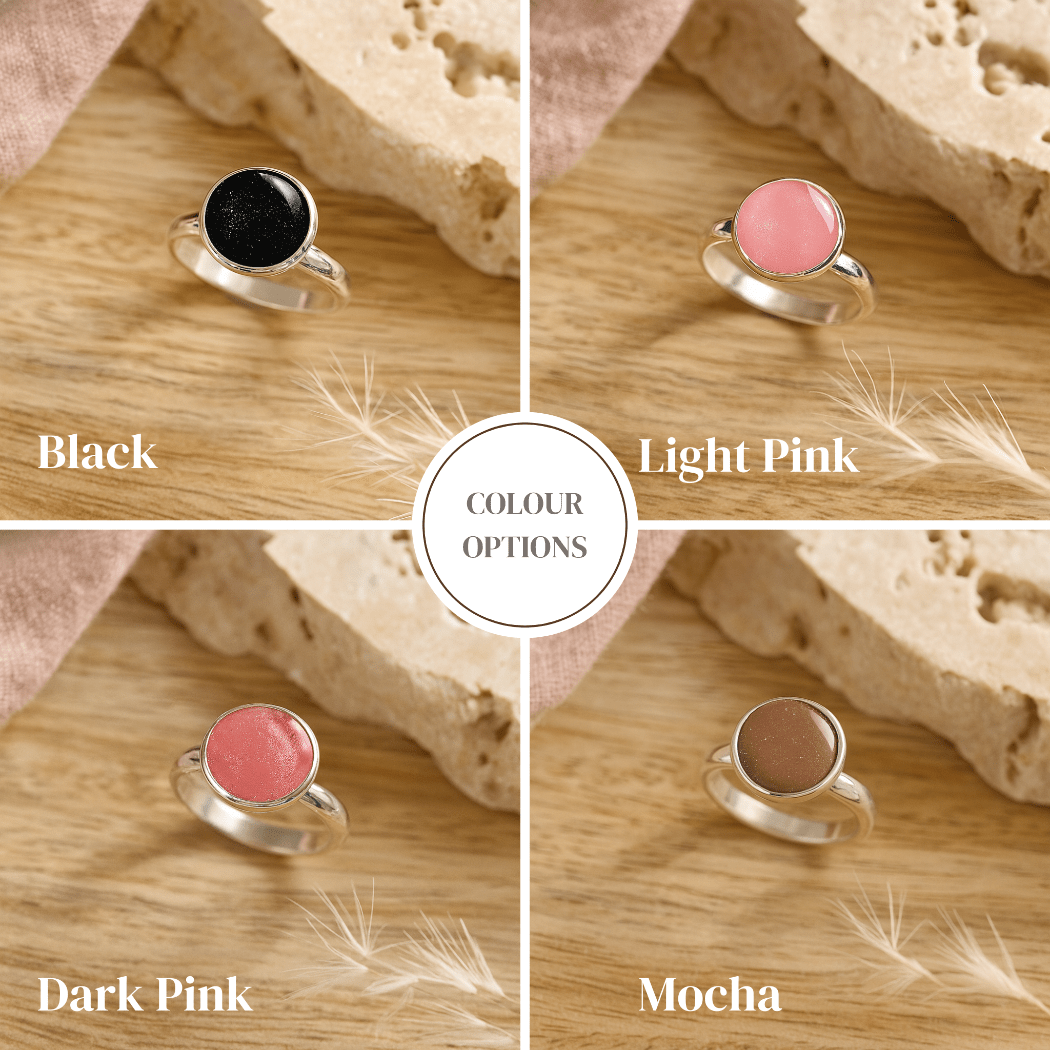 Four cremation rings options with different colored stones on a wooden surface.