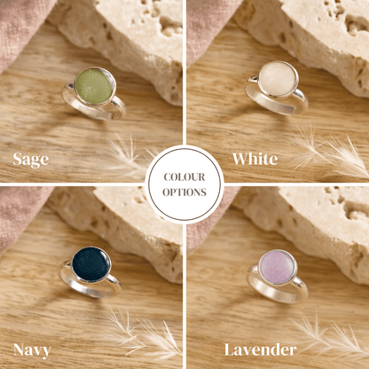 Four silver cremation rings with different colored gemstones on a wooden surface.