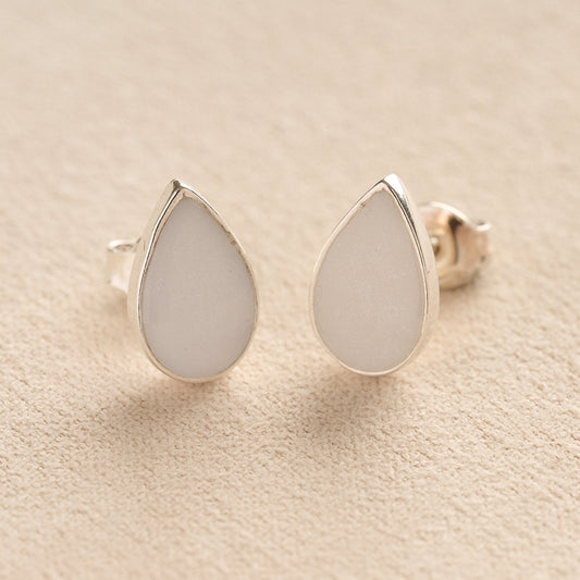 Memorial Ashes Teardrop Stud Earrings with white resin on a beige fabric background