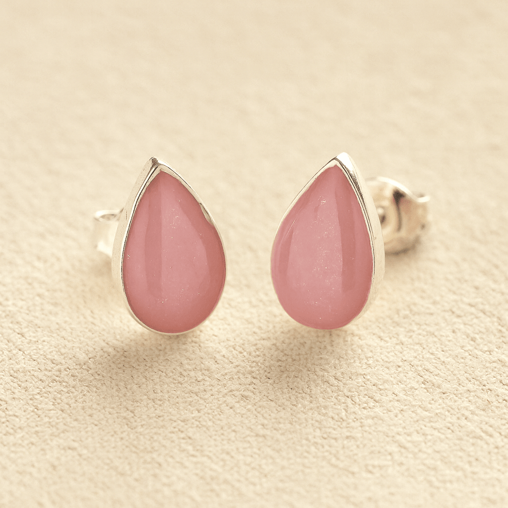 Silver Cremation Ashes Teardrop Earrings with light pink resin on a beige background