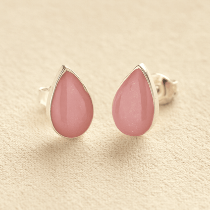 Silver Cremation Ashes Teardrop Earrings with light pink resin on a beige background