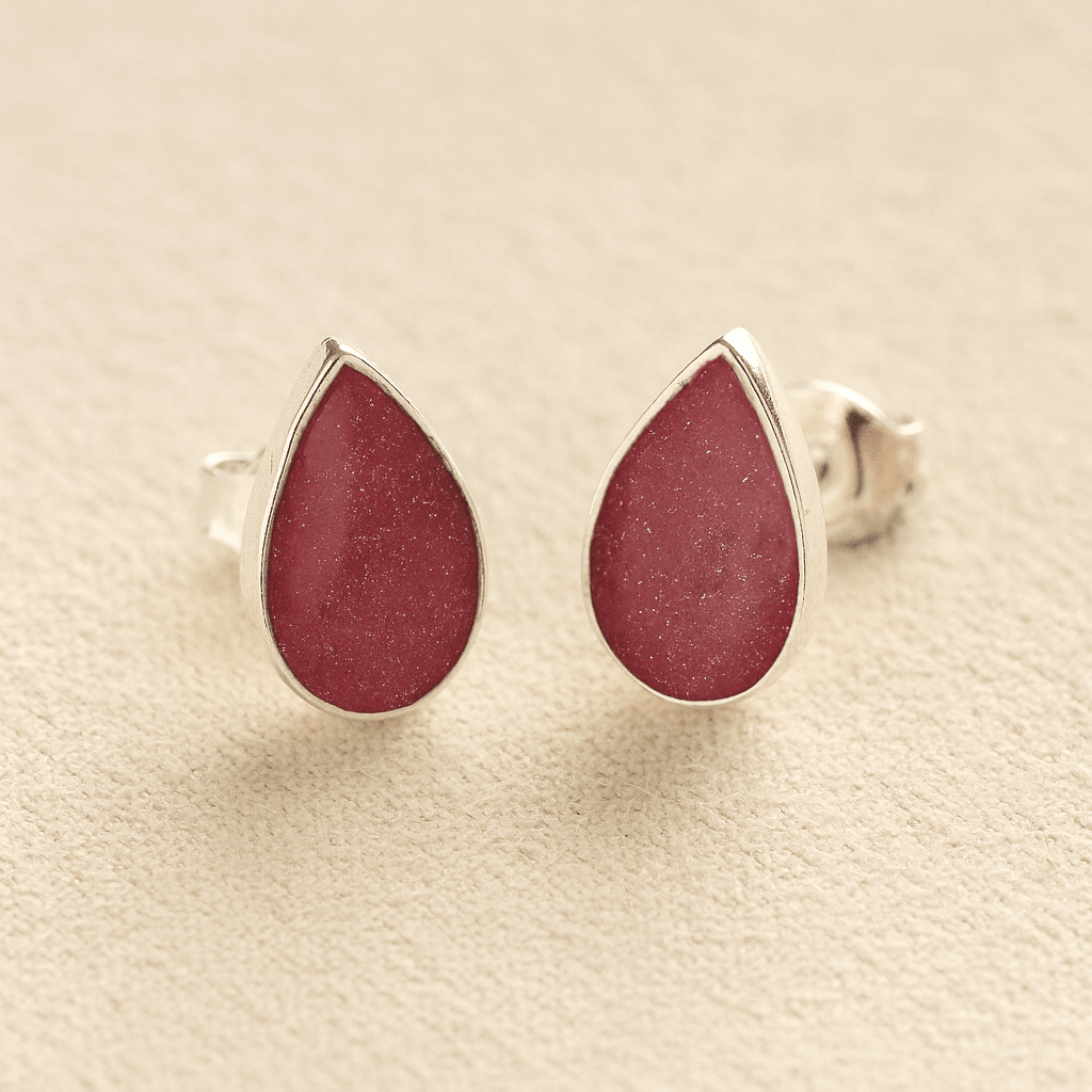 Cremation Ashes Teardrop Earrings with dark pink resin on a beige background