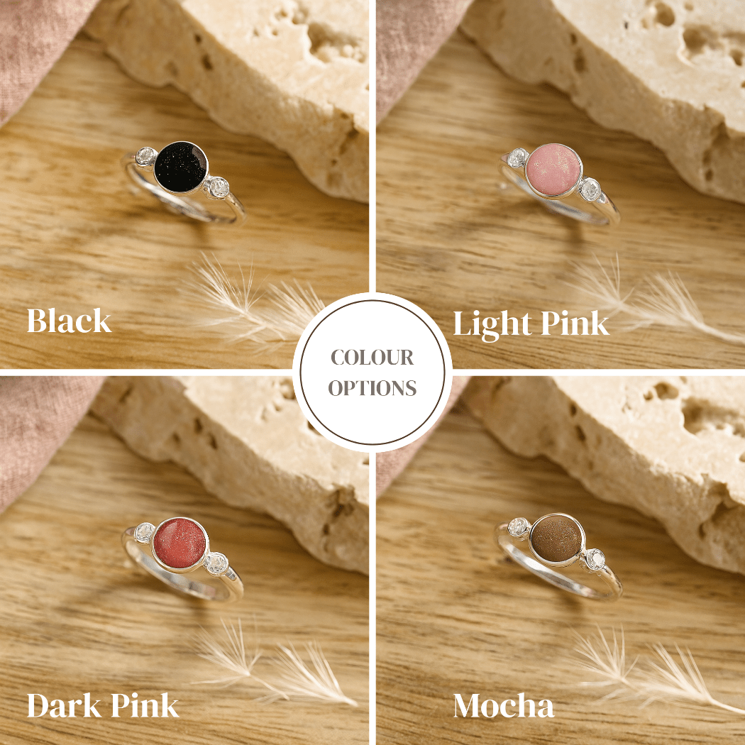Four silver ashes ring options with different colored gemstones on a wooden surface.