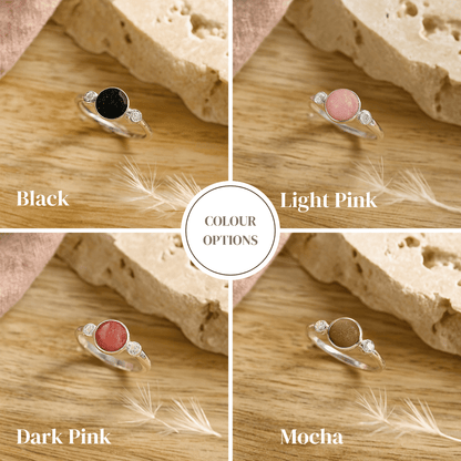 Four silver ashes ring options with different colored gemstones on a wooden surface.