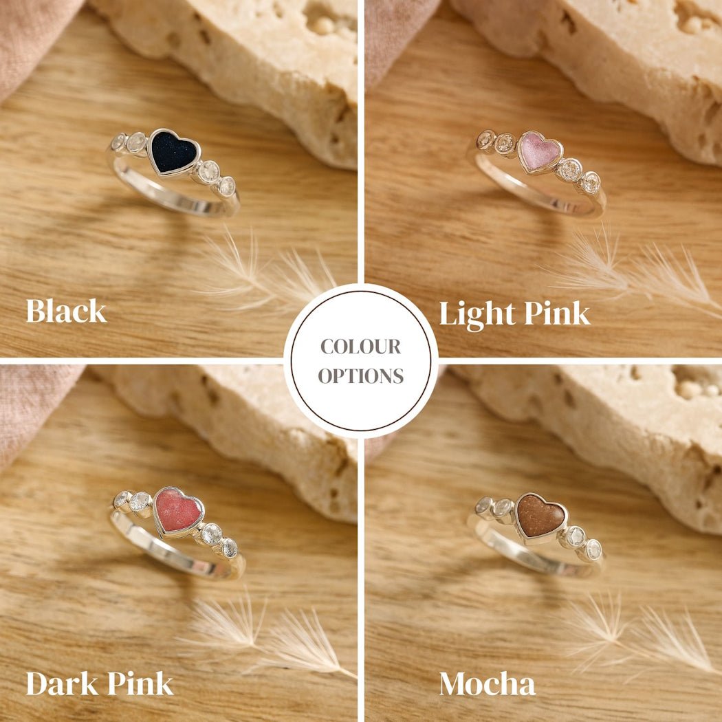 Four heart-shaped ashes rings in black, light pink, dark pink, and mocha on a wooden surface.