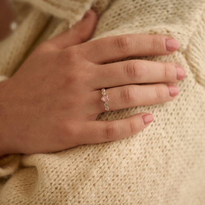 Woman wearing a pink heart cremation ashes ring with crystals while gently holding her arm