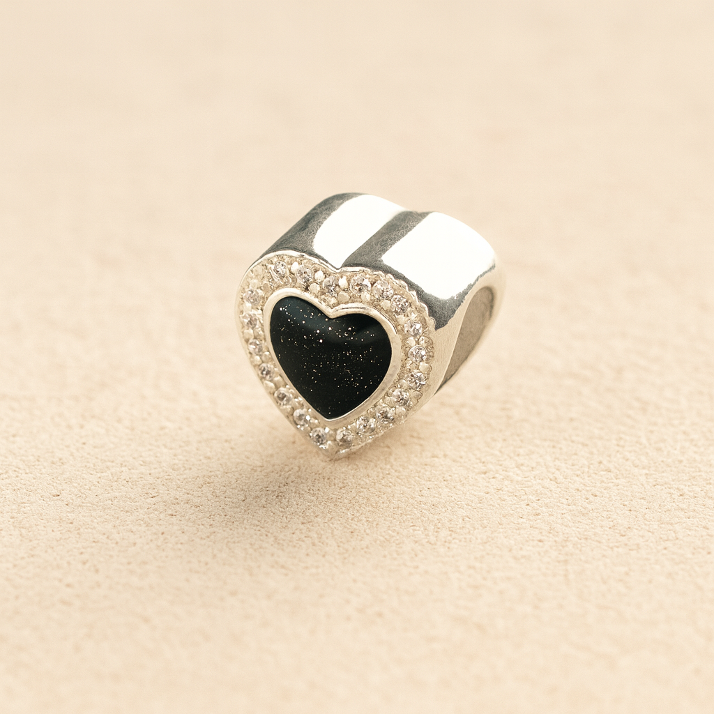 heart-shaped ashes charm with a black resin infill on a beige background 