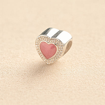 Silver Heart-shaped cremation charm with pink resin center and crystal border on beige background
