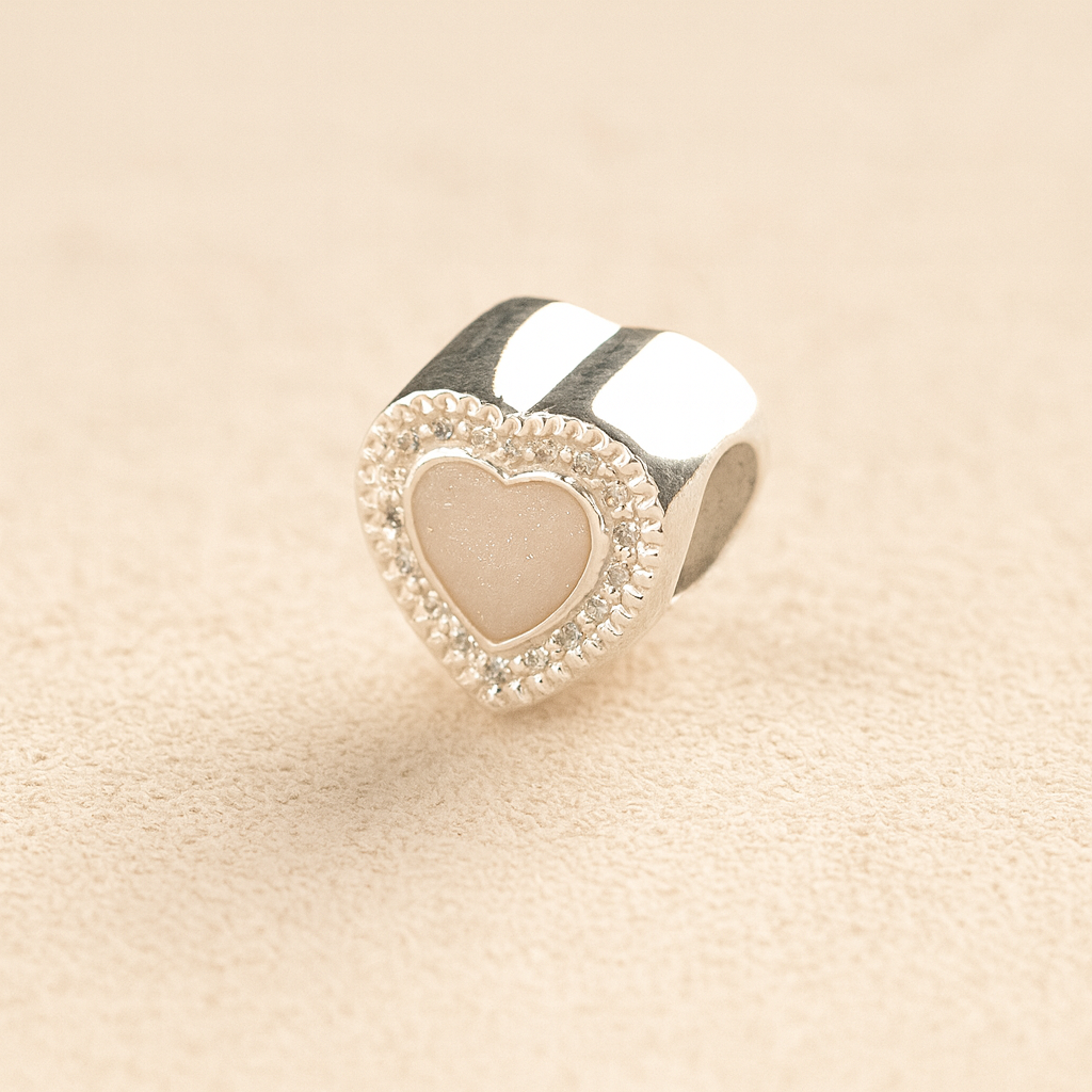 Silver Heart Pandora ashes charm with crystals and a white resin infill on a beige background