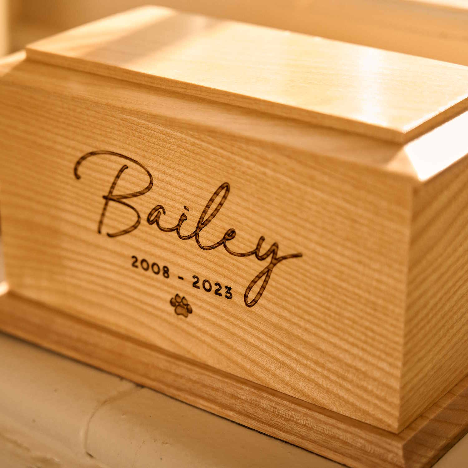 Personalised wooden pet cremation urn with engraved name and paw print