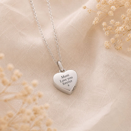 Silver heart-shaped pendant memorial necklace with engraved text on a beige fabric background