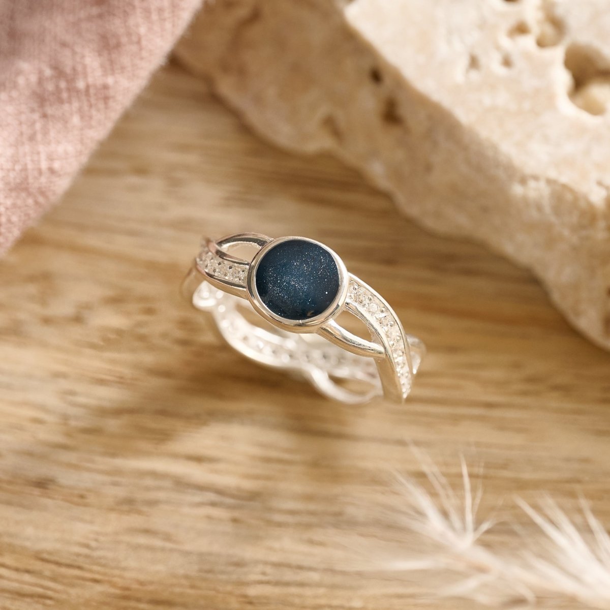 silver cremation ring with a navy resin for ashes, fur or hair on a wooden surface