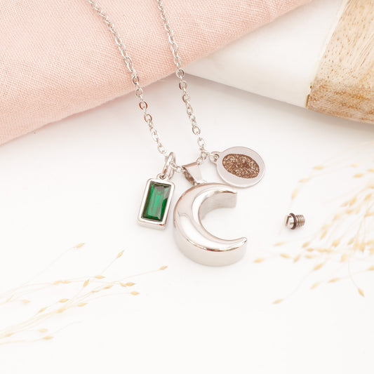 A personalised moon cremation necklace with fingerprint engraving on a table